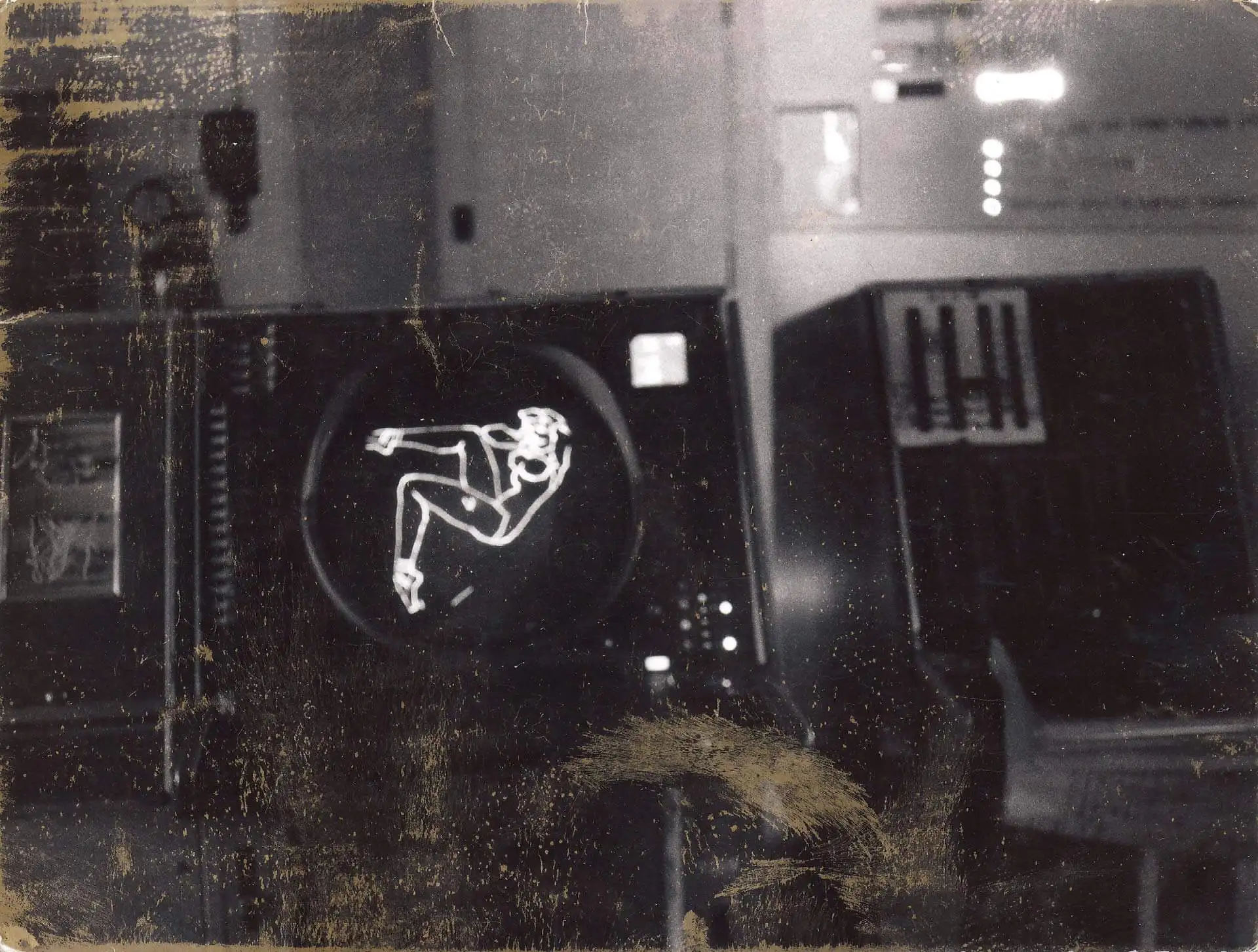 In a blurry black and white photo of antique computer equipment, a curvy woman's silhouette in a classic pinup pose is displayed in glowing white lines on a circular screen