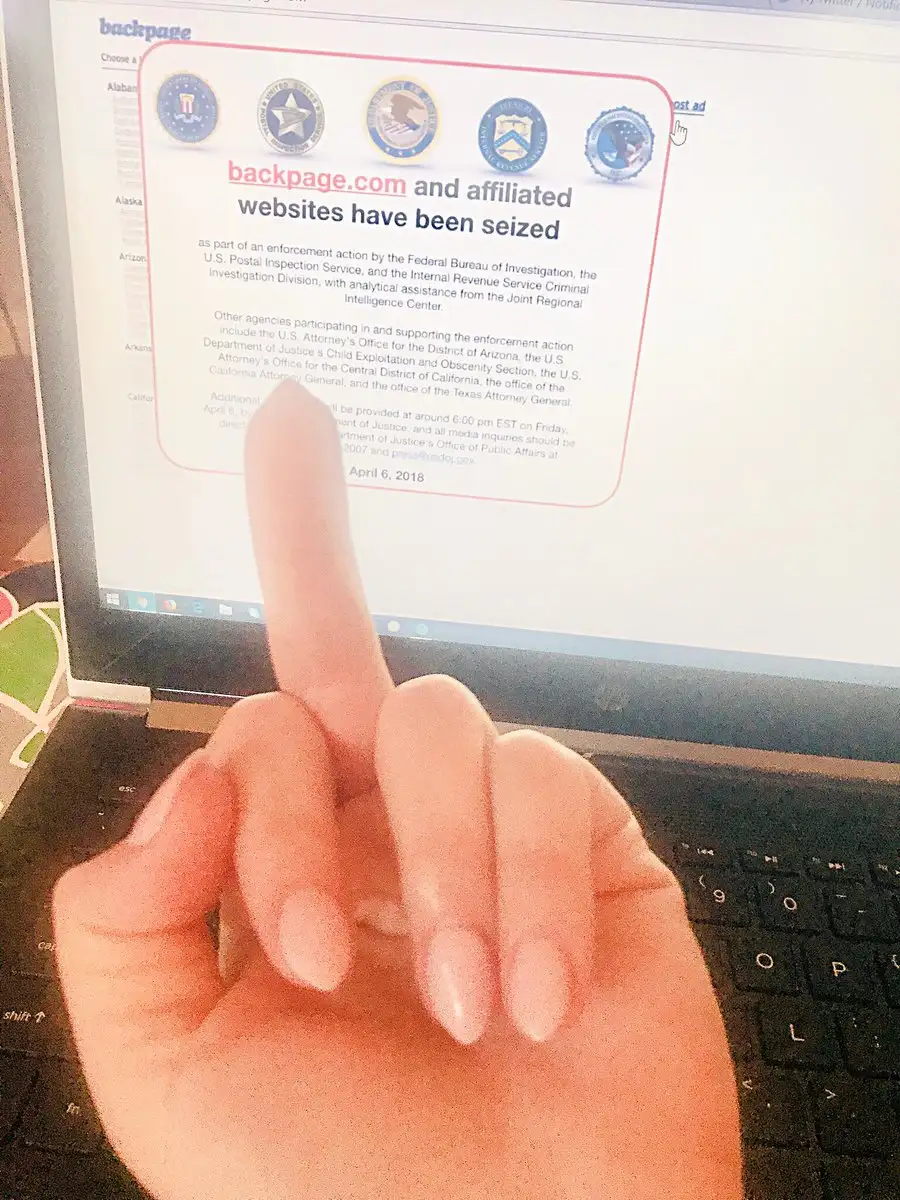 A beautifully manicured hand flips off a laptop screen showing the seized Backpage homepage
